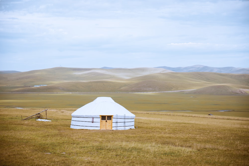 a yurt in a field with mountains in the background