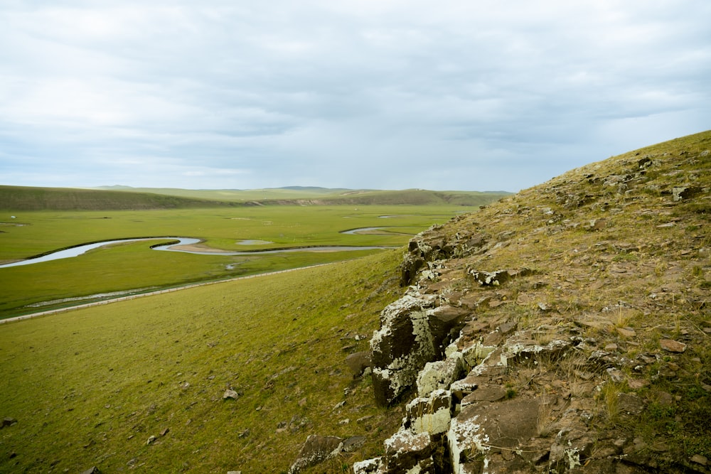 a grassy hill with a river running through it