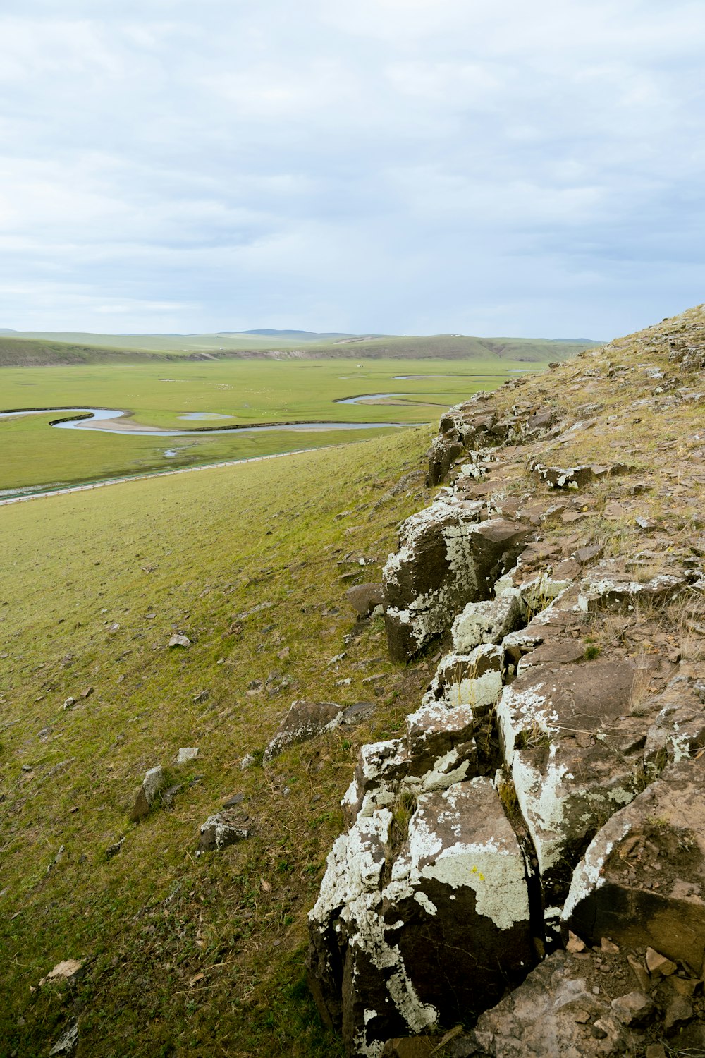 a stone wall in the middle of a grassy field