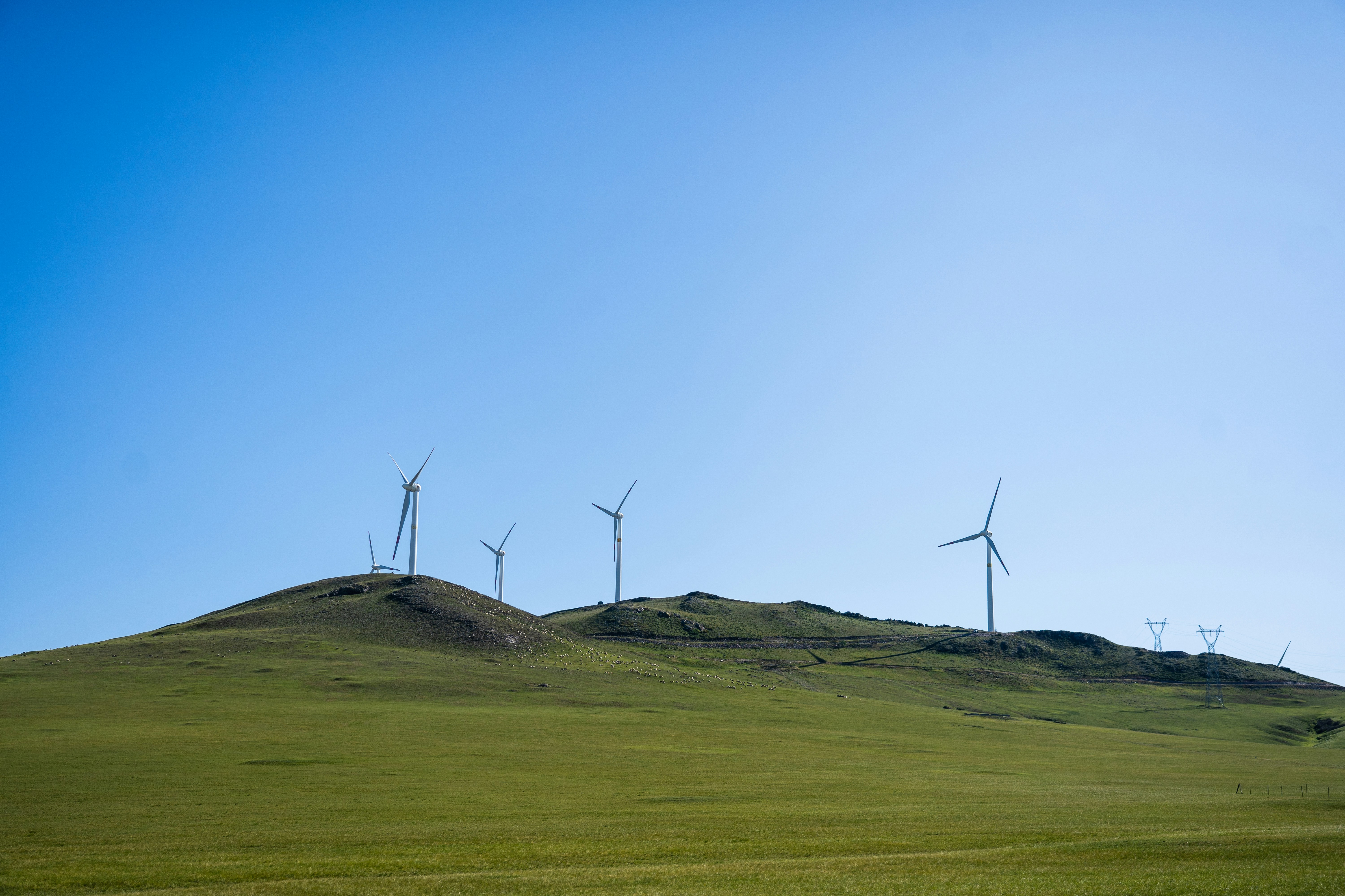 a grassy hill with several wind turbines on top of it