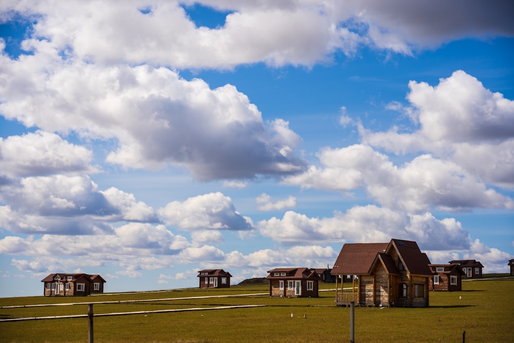 a group of houses in a field with clouds in the sky