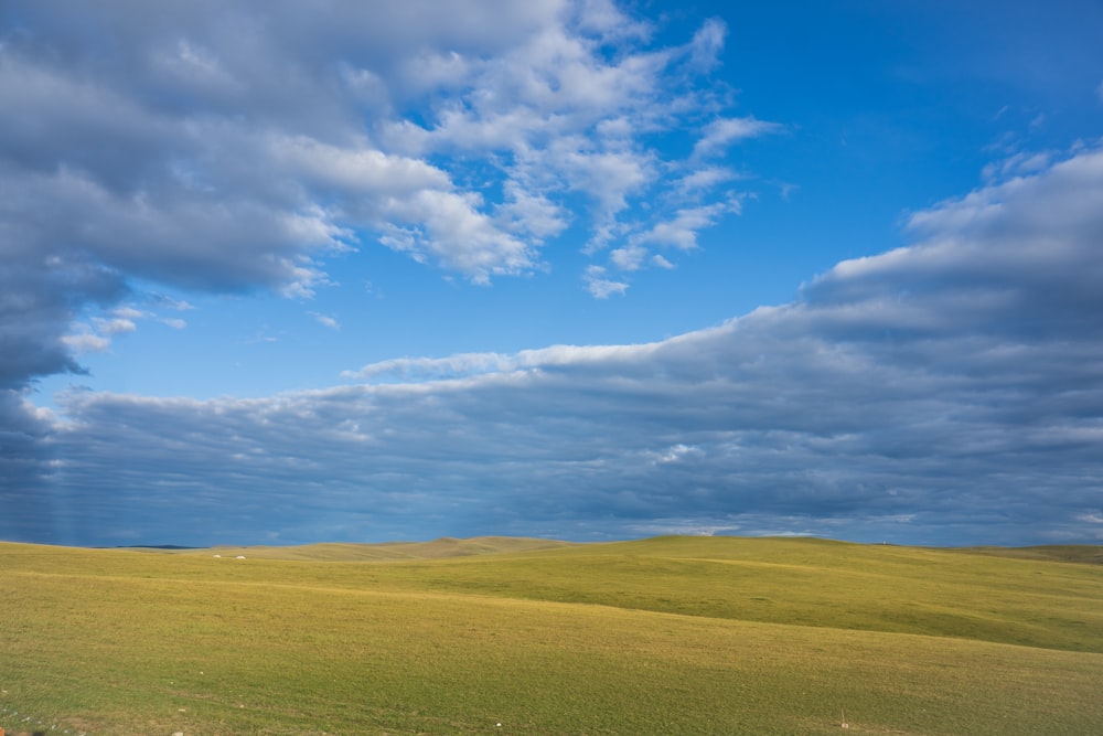 a large open field with a few clouds in the sky