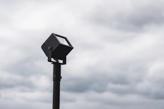 Close-up of a sturdy AC solar flood light installed outdoors in rainy weather.