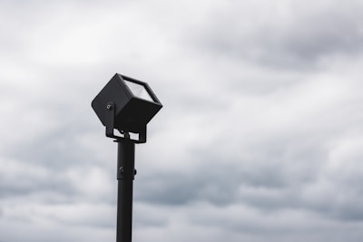 Close-up of a sturdy AC solar flood light installed outdoors in rainy weather.