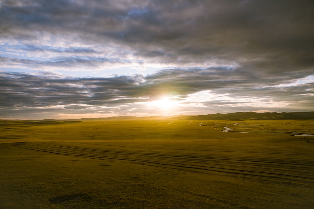 the sun is setting over a wide open field