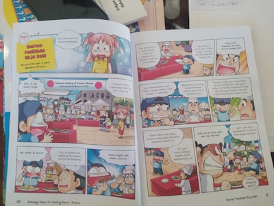 A comic book spread with colorful illustrations and multiple panels featuring animated characters. The scene depicts a cooking contest with chefs and spectators present. Speech bubbles contain dialogue in a foreign language, likely Indonesian. Characters express various emotions, such as excitement, confusion, and surprise, as they discuss aspects of the cooking event. The setting includes tables with dishes and a vibrant outdoor atmosphere.