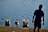 a man standing in front of a body of water with three swans