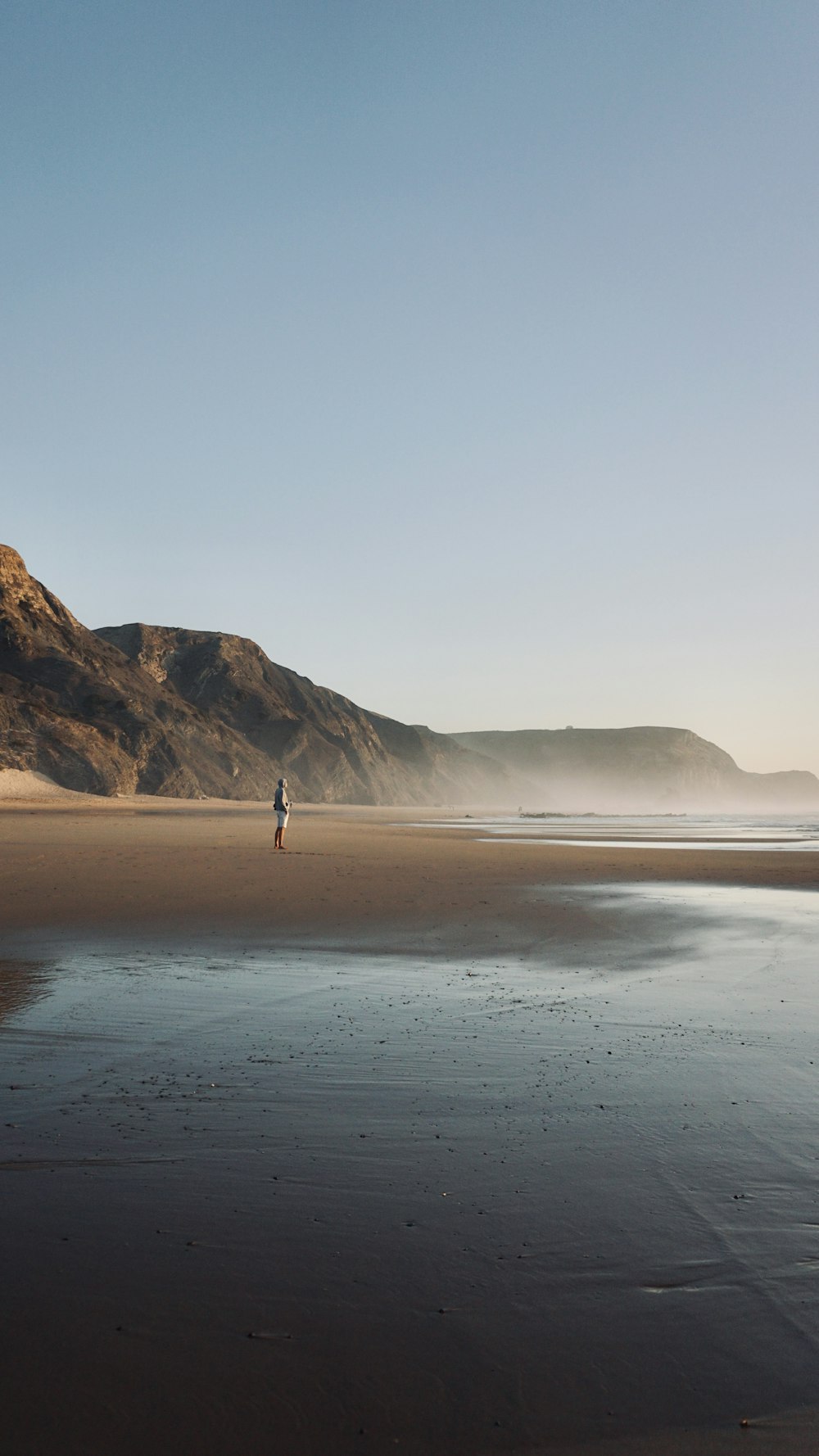 a person standing on a beach near the ocean