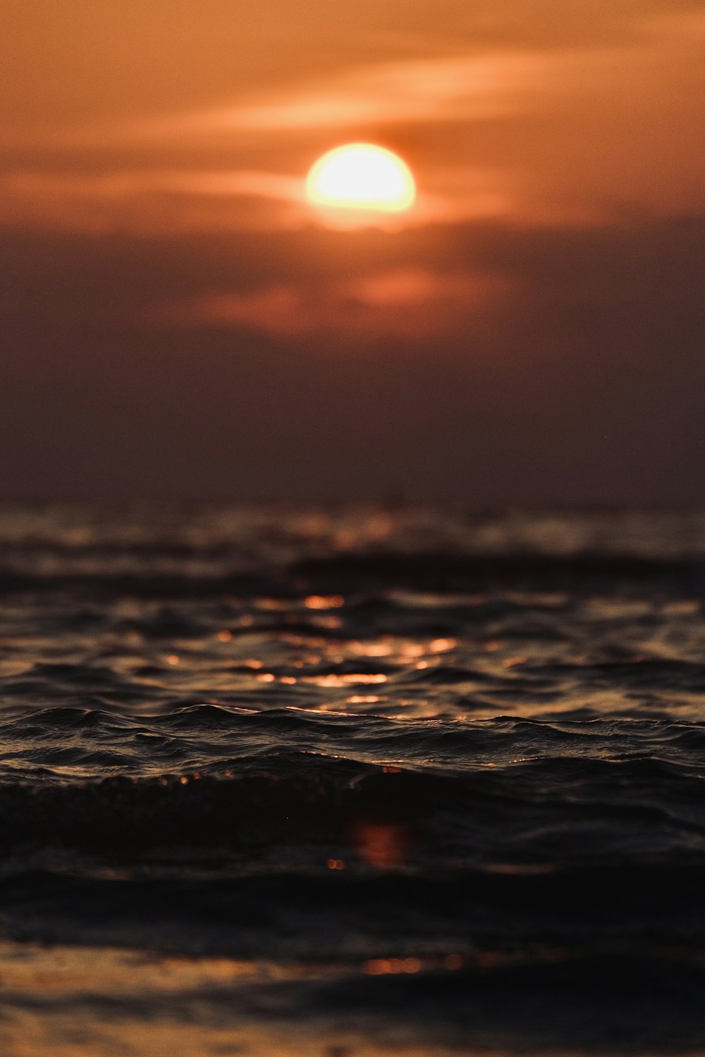 the sun is setting over the ocean with waves