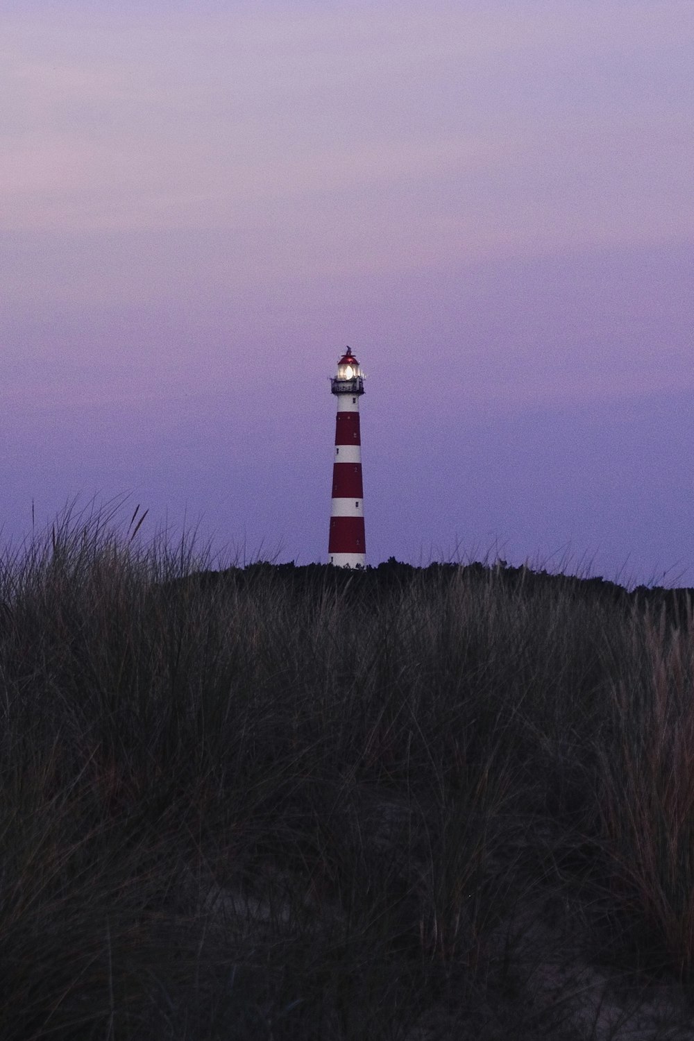 a red and white lighthouse sitting on top of a hill