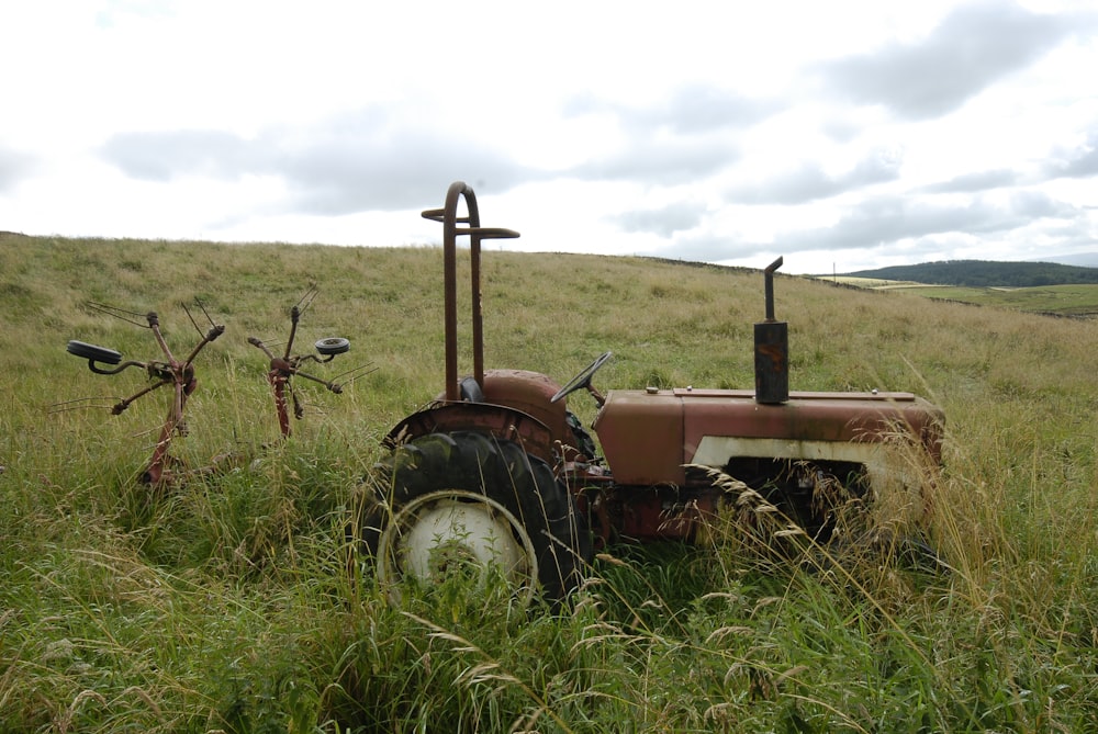 an old tractor sitting in a field of tall grass
