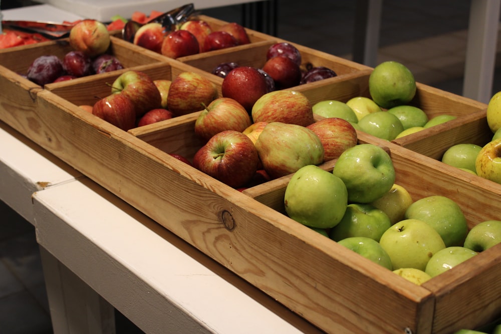 a wooden box filled with lots of green and red apples