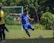 A joyful young soccer player in a blue Arena Latina jersey celebrating a goal on a sunny field.