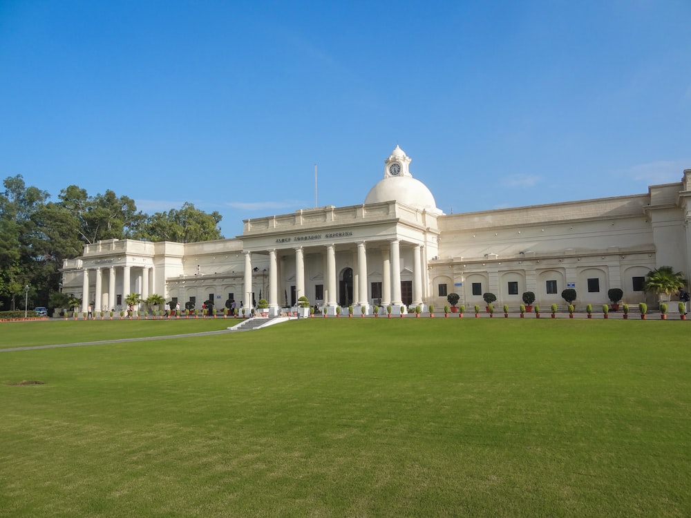 a large white building sitting on top of a lush green field