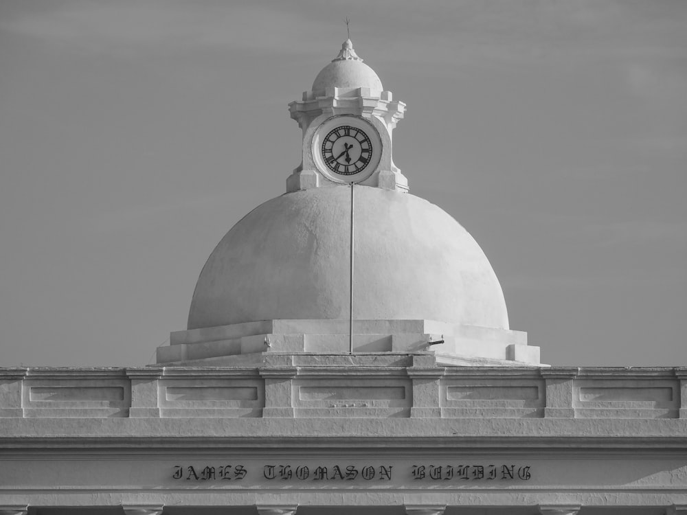 Una foto in bianco e nero di un orologio in cima a un edificio