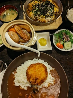 a table topped with plates of food and bowls of rice