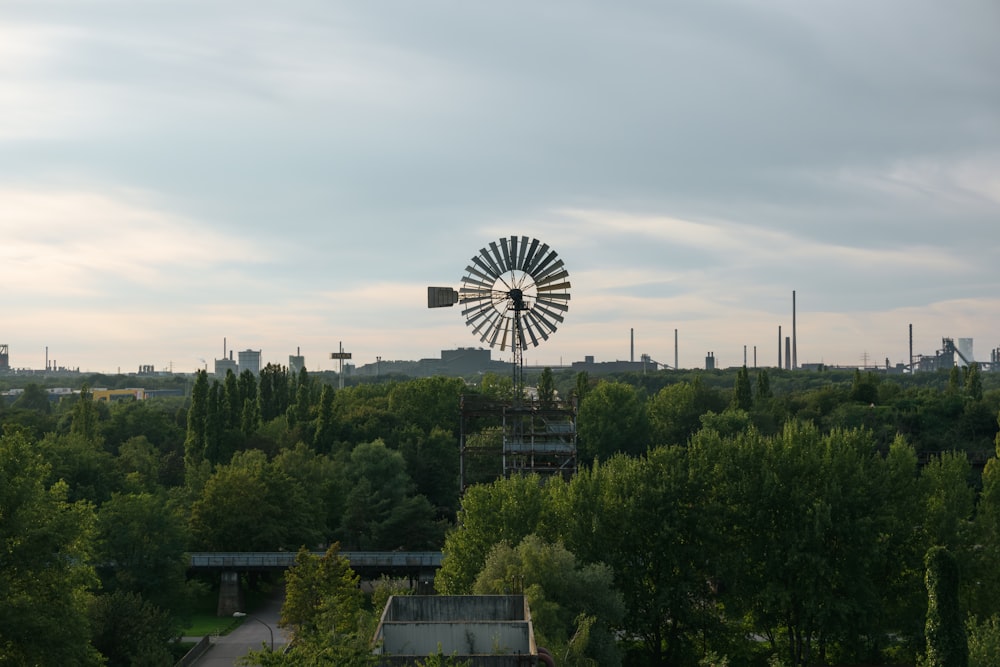 a windmill on top of a hill surrounded by trees