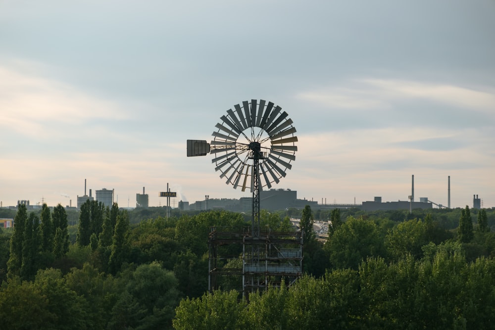 a windmill on top of a hill near a forest