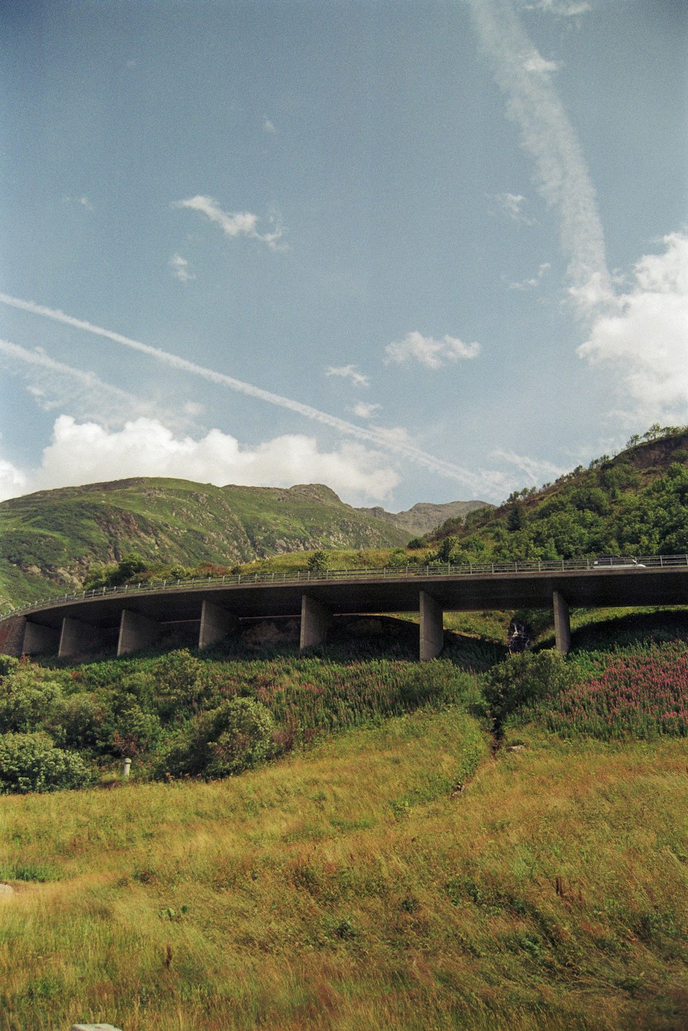 a bridge over a lush green hillside under a blue sky