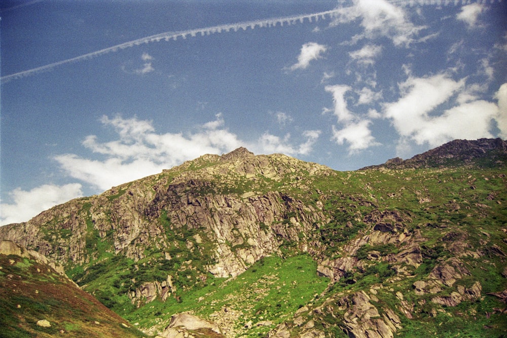 a plane flying over a lush green hillside