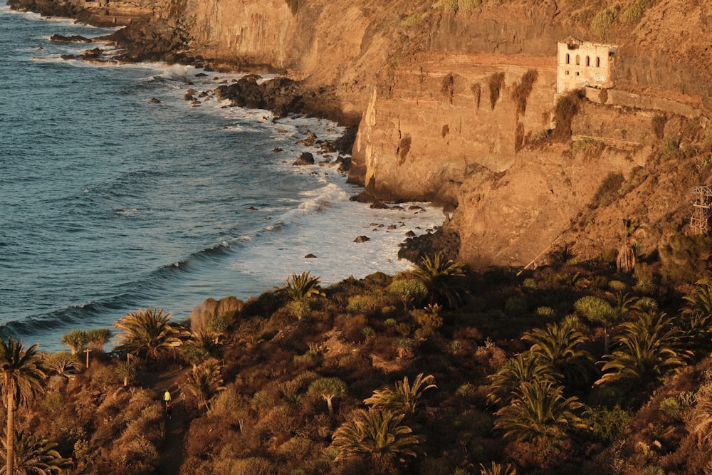 a cliff with a house on top of it next to the ocean