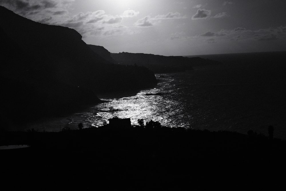 a black and white photo of the moon over the ocean