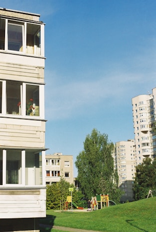 A happy family enjoying a sunny day in a green park in Rubí, with modern apartment buildings in the background.
