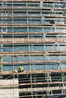 Modern office building under construction with scaffolding and workers.