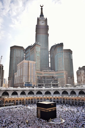 Pilgrims walking near the Kaaba in the Masjid al-Haram during sunset.