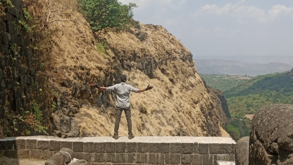a man standing on top of a stone wall