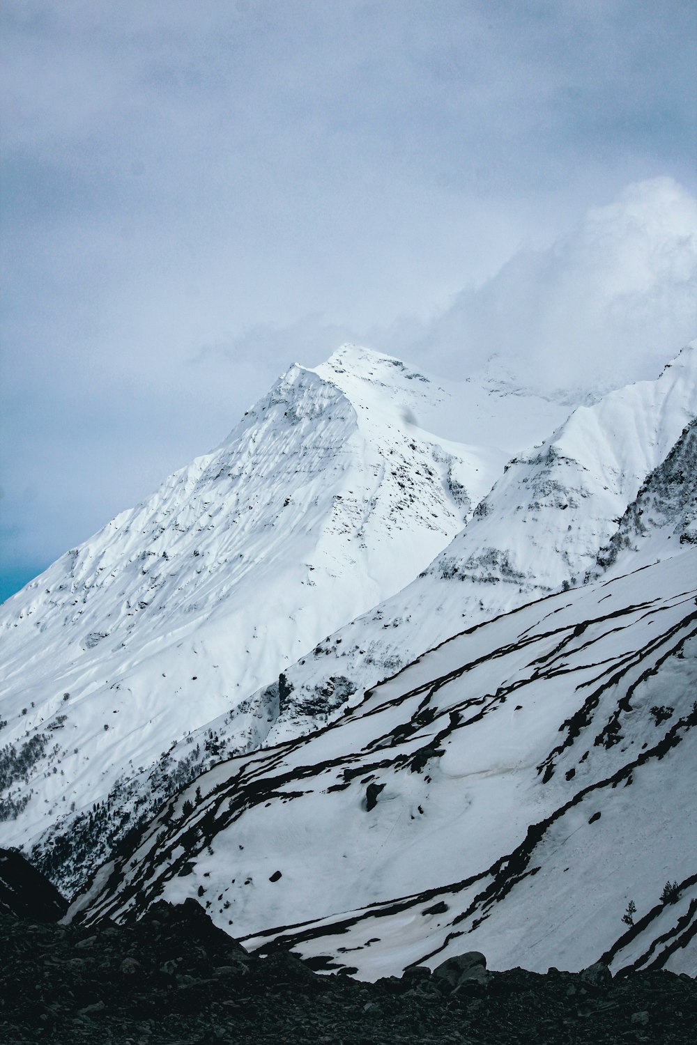 a mountain covered in snow under a cloudy sky