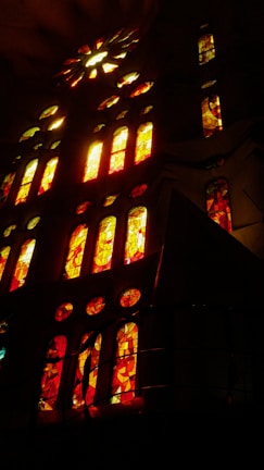 Stained glass windows glowing warmly with rich colors, casting gentle light inside a chapel.
