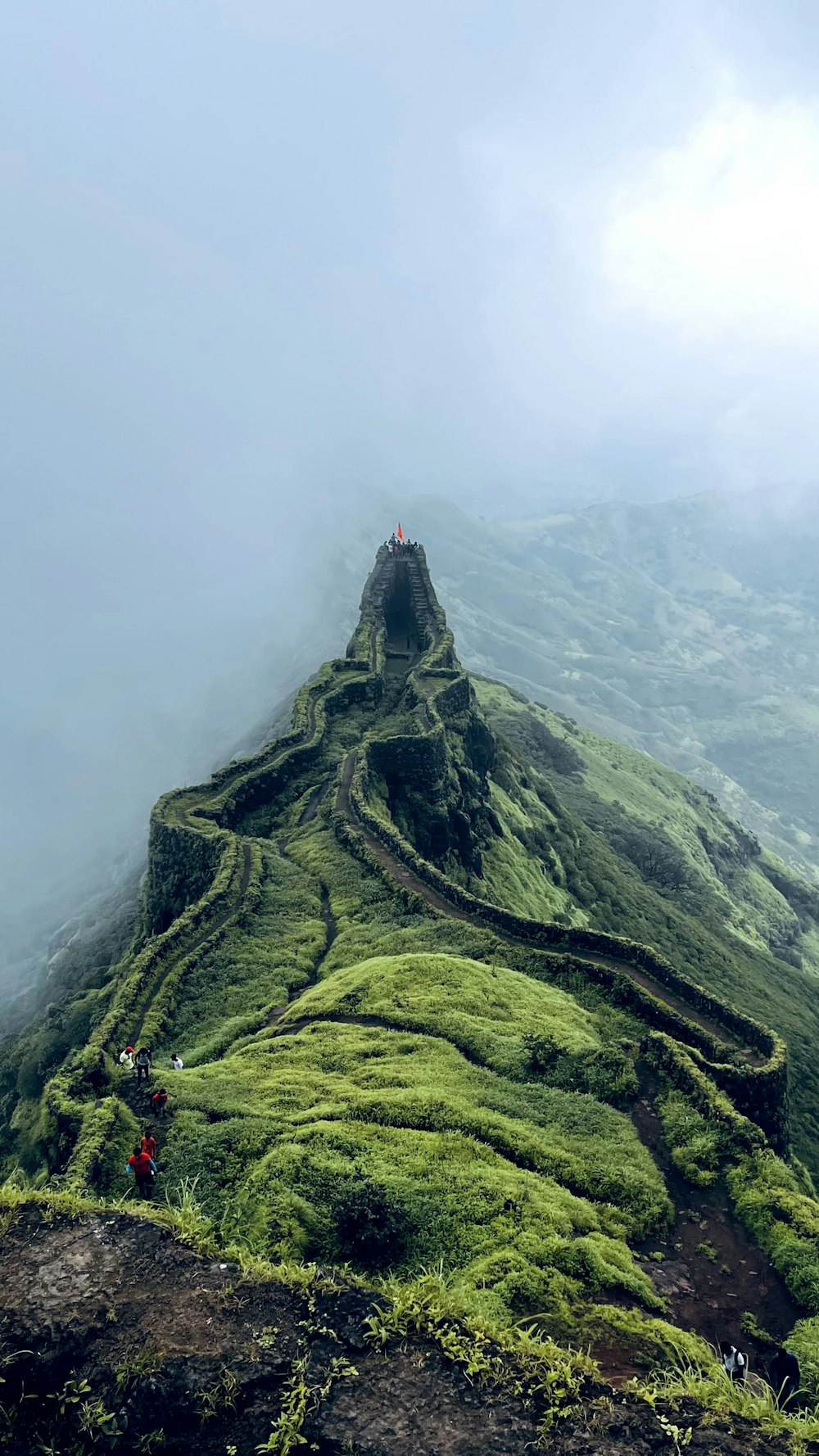 a very tall green mountain with a very steep hill