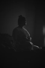 A soft, muted image of a person sitting quietly by a window, looking contemplative.