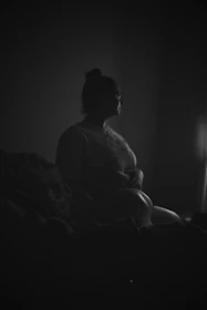A soft, muted image of a person sitting quietly by a window, looking contemplative.