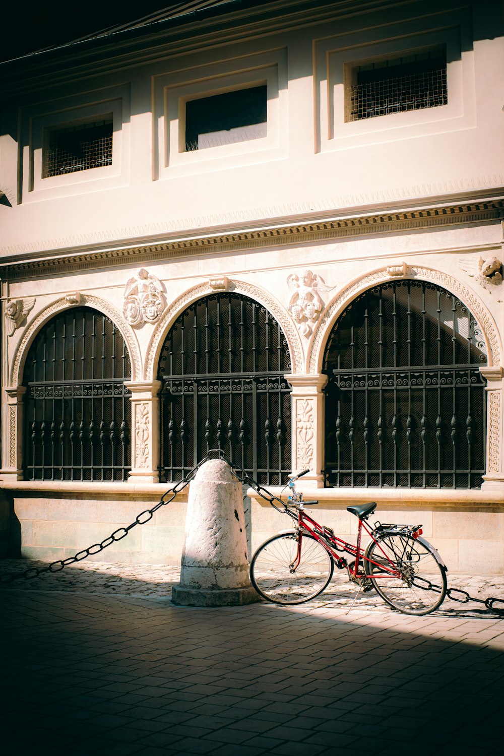 a red bike chained to a wall in front of a building