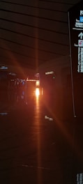 A dimly lit indoor scene featuring a corridor with a glowing light at the end, casting reflections on the surfaces. Signs with Chinese and English text are visible, including directions and labels like 'Tax Refund' and 'VIP Lounge.' The architecture is characterized by a modern and sleek design.