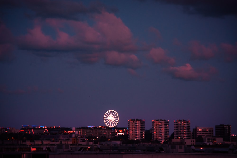 a view of a city at night with a ferris wheel in the foreground