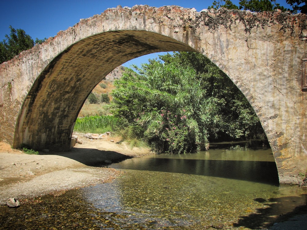 a stone bridge over a river with trees in the background
