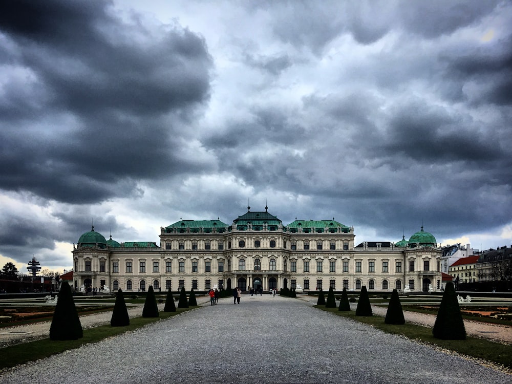 a large white building with a green roof under a cloudy sky