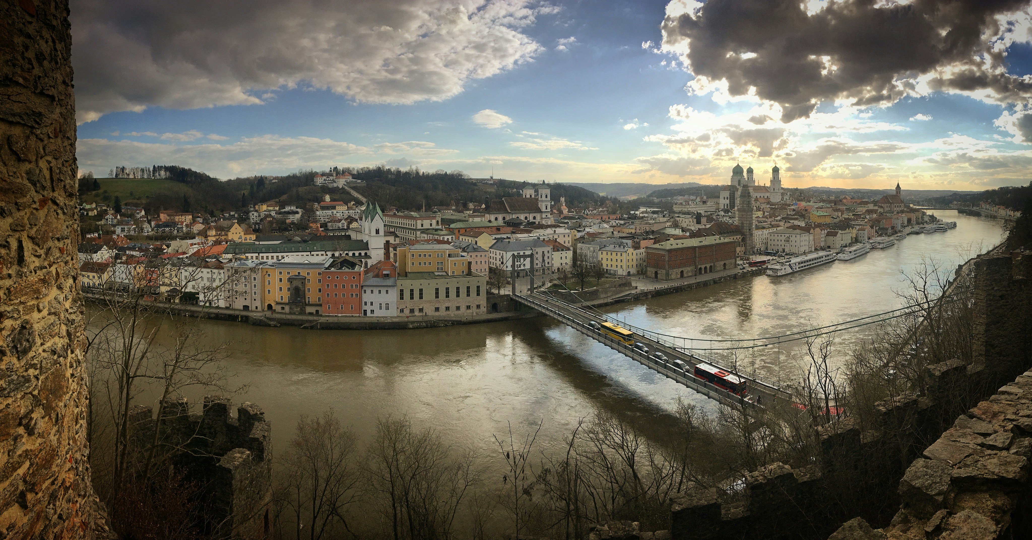 a river running through a city next to a bridge, Panorama of city Passau, Bavaria, Germany, March 2019