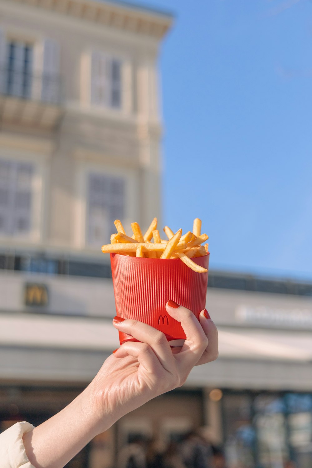 a person holding a red container with french fries in it