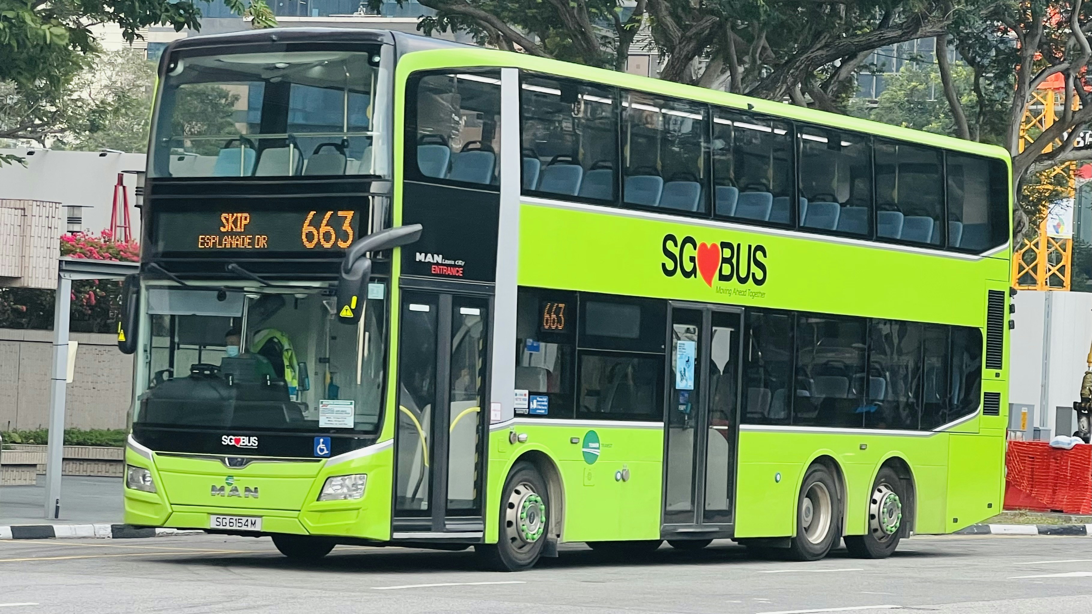 a green double decker bus driving down a street