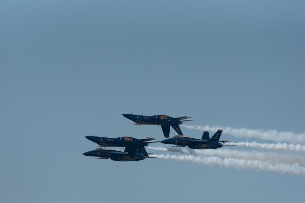 a group of fighter jets flying through a blue sky