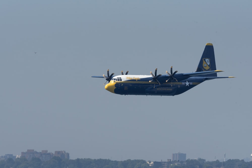 a blue and white plane flying over a city