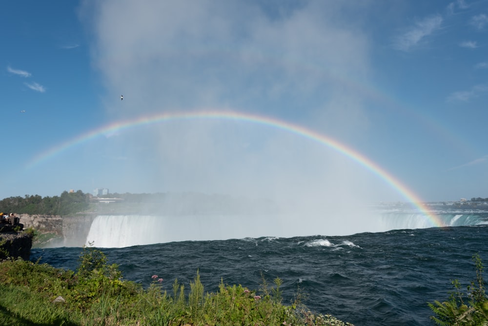 a rainbow over a waterfall and a body of water
