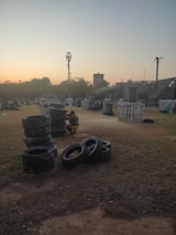Players in camouflage gear engaged in an outdoor airsoft match during sunset.