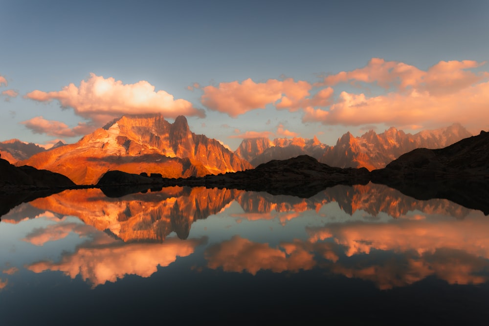 a mountain range is reflected in the still water of a lake