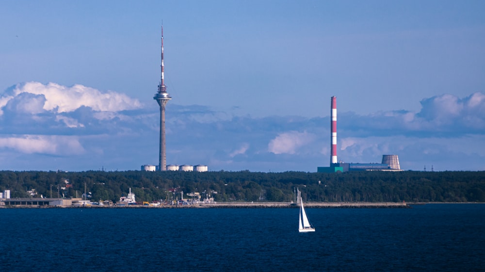 a sailboat in a body of water with a tower in the background