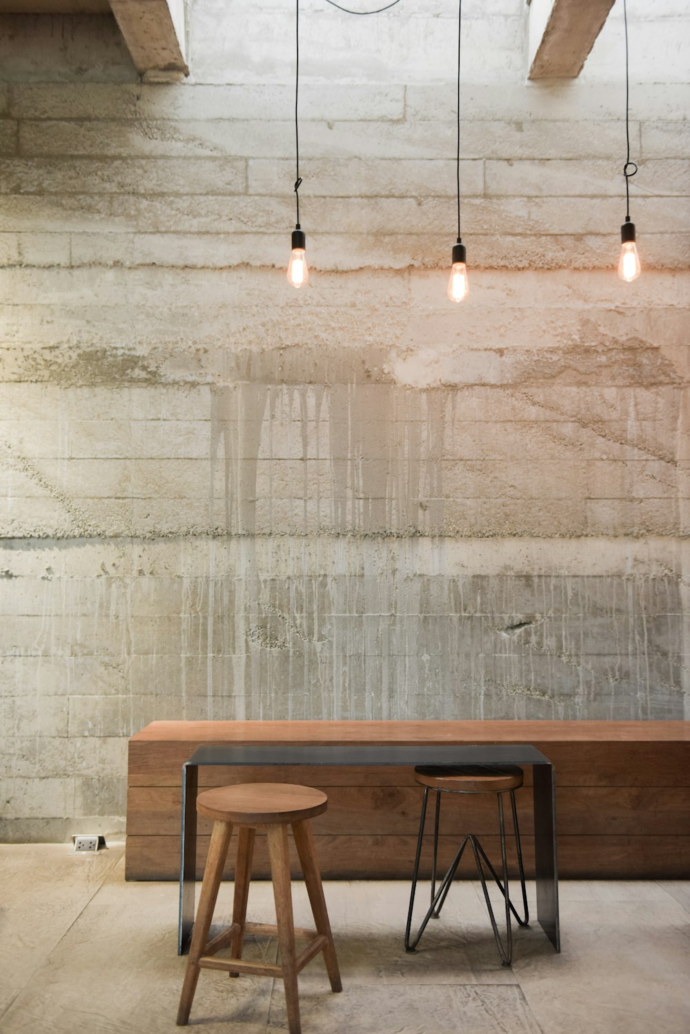 two stools and a table in front of a brick wall